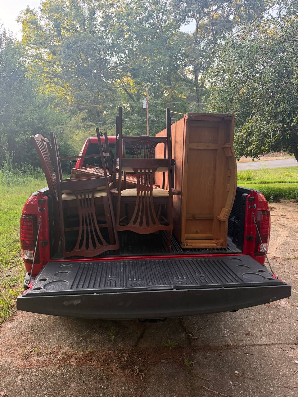 Truck bed loaded with dining chairs, a table and a dresser